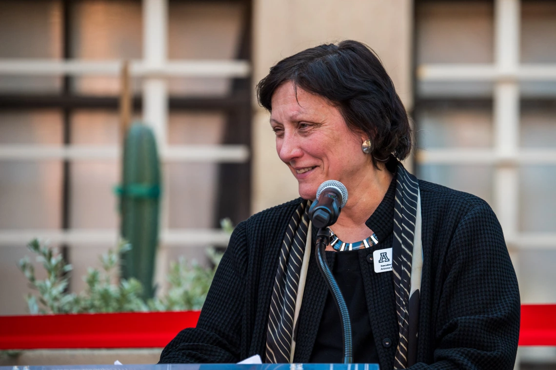 Toni Massaro speaking at a podium during the event.